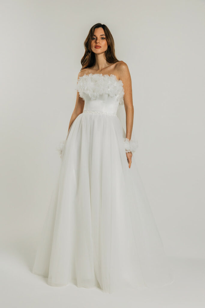 femme dans une robe de mariée A-line épurée avec des fleurs
