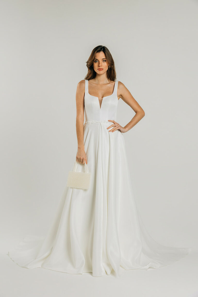 femme dans une robe de mariée A-line épurée avec un sac en perle