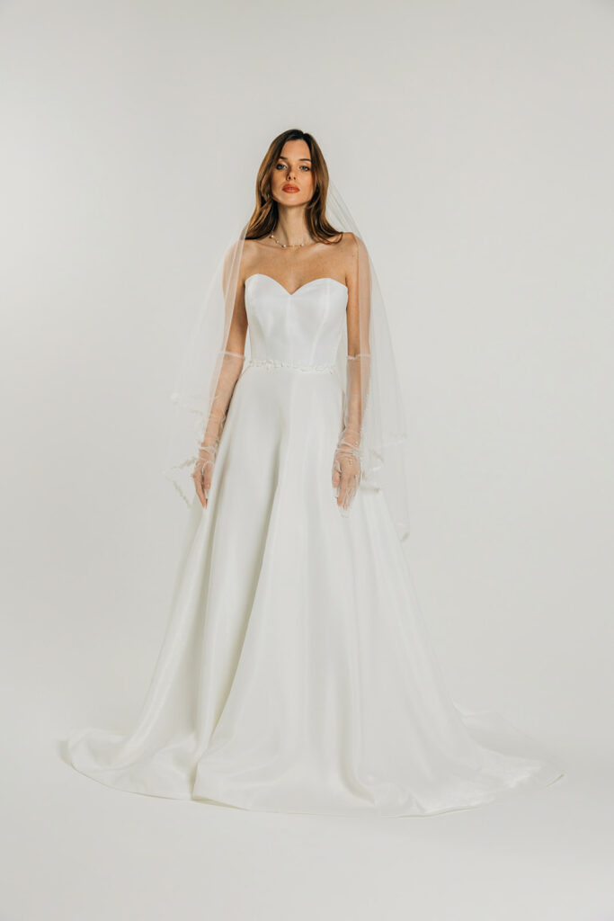 femme dans une robe de mariée A-line épurée avec décolleté cœur et un voile