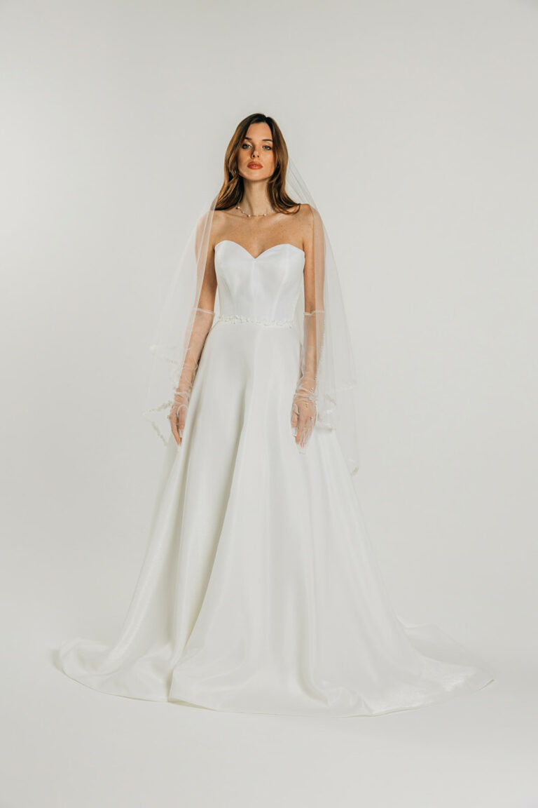 femme dans une robe de mariée A-line épurée avec décolleté cœur et un voile